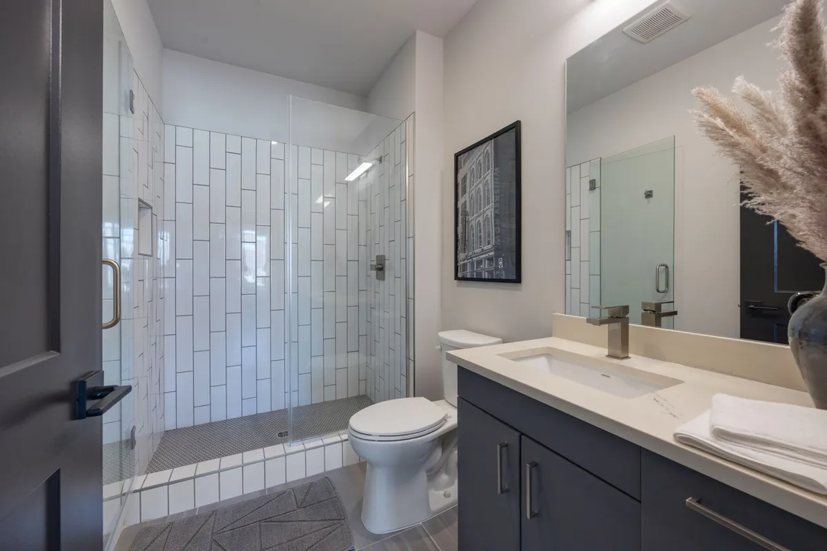 A contemporary bathroom showcasing a sleek vanity with a sink, glass-enclosed shower, and modern framed artwork. The spa-like setting feels refreshing and serene, echoing the idea of a rejuvenating personal sanctuary.