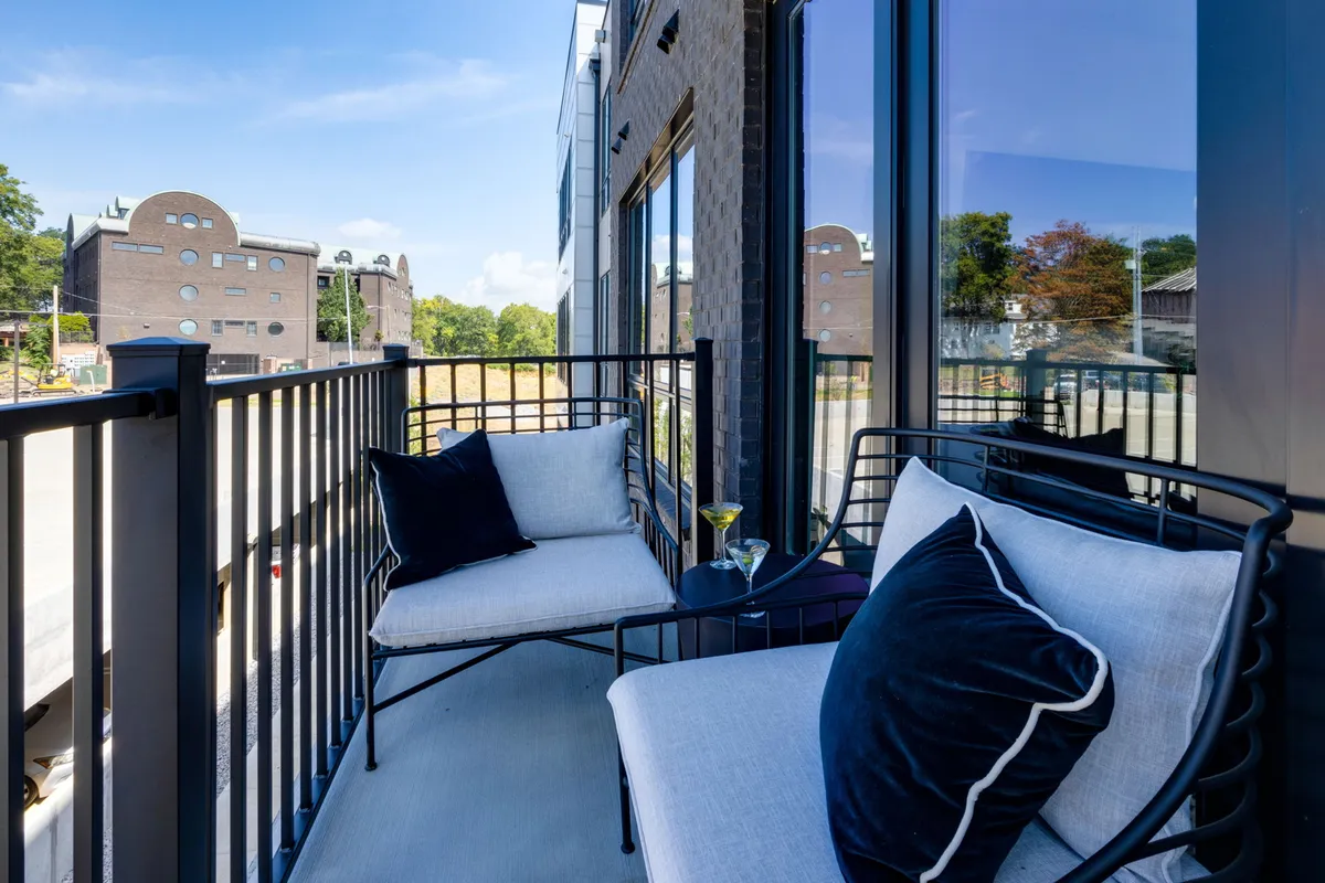A private balcony with chic seating, a cocktail glass on the table, and a sweeping urban view of Nashville. The setting is casual and relaxed, inviting you to take in the city skyline and enjoy an evening under the stars.